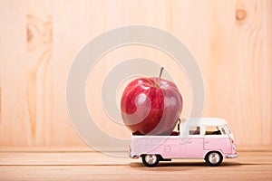 Apple red on toy car with wood floor background