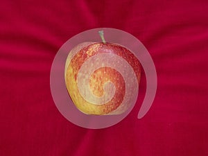 Apple on red velvet cushion, temptation or luxury, with copyspace.