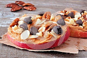 Apple rounds close up with peanut butter, chocolate and nuts