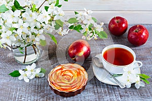Apple shaped roses pie and cup of tea on wooden table