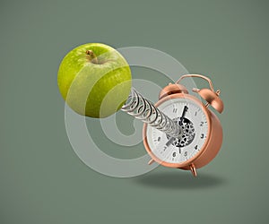 Apple on spring coming out of alarm clock