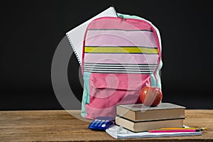 Apple on stack of books with calculator and school bag