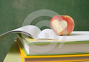 Apple on stack of books next to a chalk Board