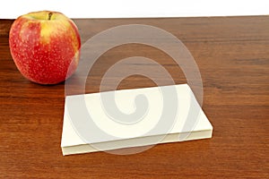 An apple with a stack of paper is on the table