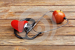 Apple, stethoscope and heart on wooden background