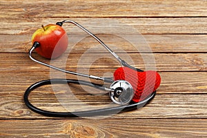 Apple, stethoscope and heart on wooden background