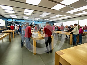 An Apple store with people waiting to purchase Apple Macbooks, iPads and iPhones