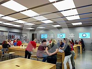 An Apple store with people waiting to purchase Apple Macbooks, iPads and iPhones