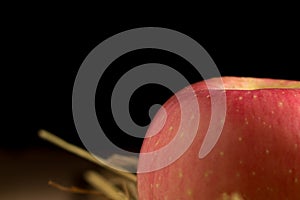 apple. straw. on wood. black background