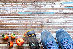 Apple, Strawberries, bottle of water and running shoes on rusty wood background. Active healthy lifestyle concept background