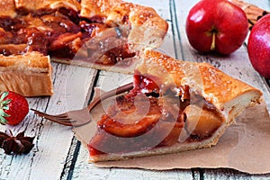 Apple strawberry autumn pie, close up table scene with a white wood background