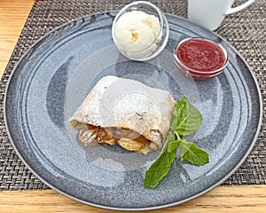 Apple strudel and ice cream with strawberry topping