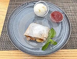 Apple strudel and ice cream with strawberry topping