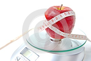 Apple and tape measure on a scale