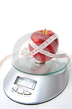 Apple and tape measure on a scale