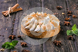 Apple tart with meringue and lime peel on a wooden stand