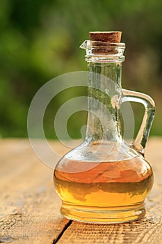 Apple vinegar in glass bottle on wooden boards with green natural background