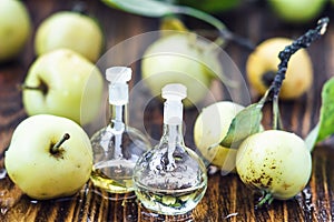 Apple vinegar in glass jar with ripe green fruit. Bottle of apple organic vinegar on wooden background. Healthy organic food.