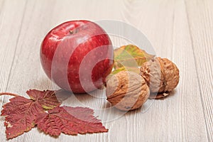 Apple, walnuts and dry leaves in an autumn still llife