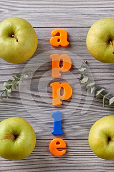 Apple word and green apples on grey table.