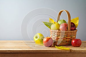 Apples in basket on wooden table. Autumn and fall harvest background