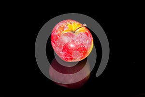 Apples on black wavy mirror.