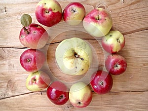 Apples in a circle and in the middle an apple on a wooden table
