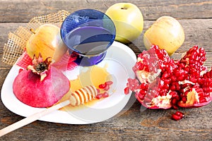 Apples, cut red pomegranate and honey. Jewish New Year Holiday, Rosh Hashanah food symbols on the old wood