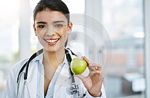 Apples are extremely rich in important antioxidants. Portrait of a young female doctor holding an apple.