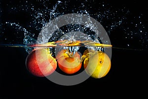 Apples falling and splashing into clear water