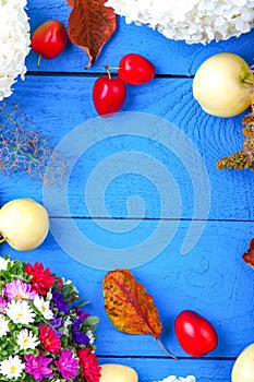 Apples, flowers, leaf litters and plums on a blue table