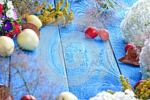 Apples, flowers, leaf litters and plums on a wood table