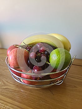 Apples, grapes, bananas and limes in a fruit bowl
