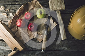 Apples, hard hat and tools at the work bench carpenter