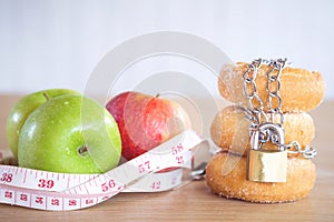 Apples with measuring tape and donuts with chain and lock on desk