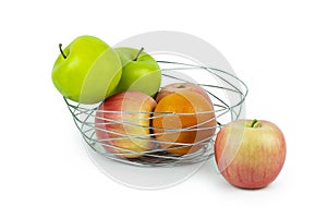 Apples and oranges in a decoratively wire basket put on isolated white background and there is an apple outside the wire basket.