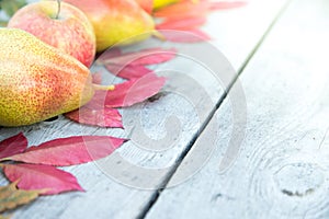 apples, pears and autumn leaves on wooden background. Autumn background
