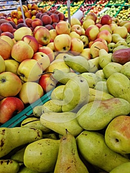 Apples and pears in plastic boxes in a store, close-up