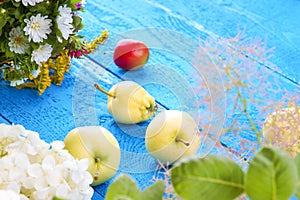 Apples, plum and flowers on a wooden table
