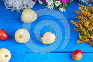 Apples, plums and flowers on a table