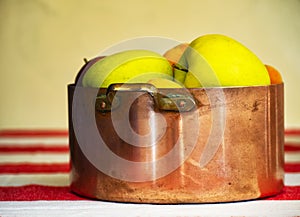 Apples, prunes and apricots in old copper pot and wooden bowl on the background