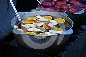 Apples, spices and citrus fruits in a pan with mulled wine.