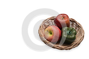 Apples and sweet pepper in wicker basket isolated on white background.