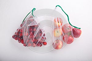 Apples in textile grocery mesh bags. Red fruits and vegetables in reusable eco friendly packaging on white background