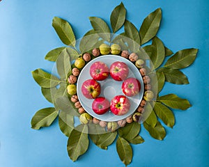 Apples and walnuts on a plate surrounded by green leaves