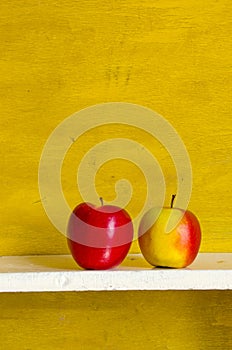 Apples on white shelve yellow wall background.