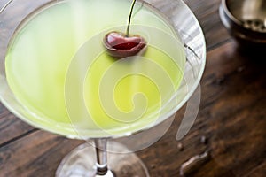 Appletini Cocktail with cherry on wooden surface.