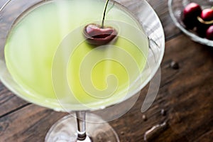 Appletini Cocktail with cherry on wooden surface.