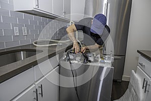 Appliance repairman installing dishwasher hoses