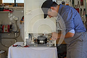 Appliance service technician in his workshop repairing a faulty refrigerator. Technician at work